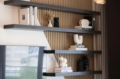 a shelf with vases and books on a wall at Brand New 1BR with Pool, Sauna & Gym in Dubai