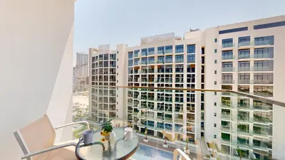 a balcony with a table and a large building at Azizi Riviera 47 - Comfortable Studio in Meydan in Dubai