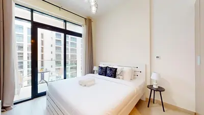 a bedroom with a white bed and a large window at Azizi Riviera 47 - Comfortable Studio in Meydan in Dubai