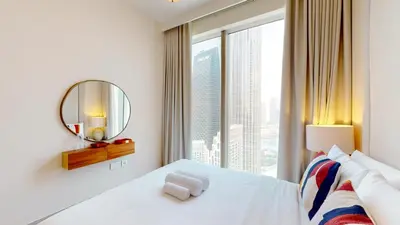 a bedroom with a white bed with a large window at Locations I Spacious Modern 3 Bedroom I Luxury Stay Near Dubai Mall & Burj Khalifa I Pool, Gym, Parking & Wi-Fi in Dubai