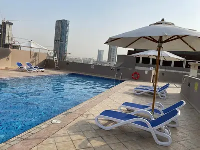a pool with two lounge chairs and an umbrella at Homes2Retreat - Studio in Lincoln Park Sheffield in Dubai