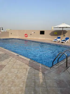 a large swimming pool with chairs and an umbrella at Homes2Retreat - Studio in Lincoln Park Sheffield in Dubai