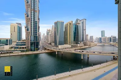 a bridge over a river in a city with tall buildings at Spacious and Peaceful 1BR with Canal views in Dubai