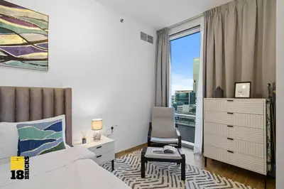 a bedroom with a bed and a chair and a window at Spacious and Peaceful 1BR with Canal views in Dubai