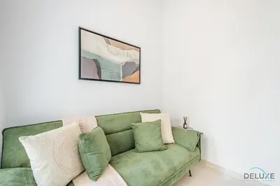 a green couch with pillows in a living room at Stylish 1BR Apartment in Damac Hills 2 Avencia 45, Dubailand by Deluxe Holiday Homes in Dubai