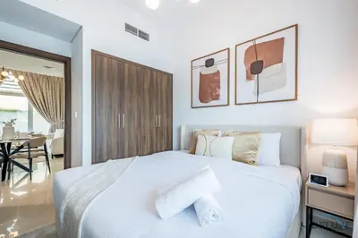 a bedroom with a white bed and a dining room at Stylish 1BR Apartment in Damac Hills 2 Avencia 45, Dubailand by Deluxe Holiday Homes in Dubai