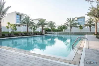 a swimming pool with palm trees and a building at Stylish 1BR Apartment in Damac Hills 2 Avencia 45, Dubailand by Deluxe Holiday Homes in Dubai