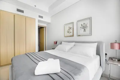 a bedroom with a large white bed with a pillow on it at Goldbest - Aykon City 2bdr in Dubai