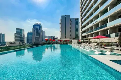 a swimming pool with chairs and umbrellas in a city at Canal View Studio Downtown - Near Dubai Mall & Burj Khalifa - MAG 318 in Dubai