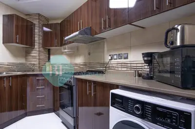 a large kitchen with wooden cabinets and a appliance at Bloomfields Modern 2br In Arabian Gate in Dubai
