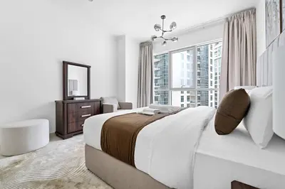 a white bedroom with a large bed and a window at Spacious 1 BR Apartment Near in Dubai