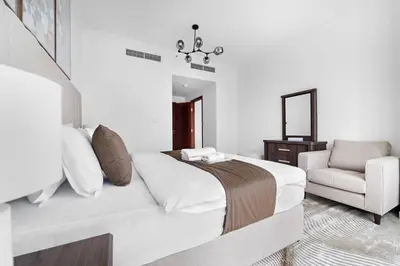 a bedroom with a bed and a chair and a mirror at Spacious 1 BR Apartment Near in Dubai