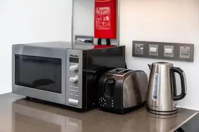 a microwave sitting on a counter next to a coffee pot at Aesthetic 1Br Chrystal Lagoon in Dubai