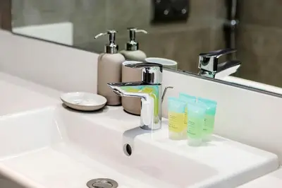a bathroom sink with a faucet and two cups at Aesthetic 1Br Chrystal Lagoon in Dubai
