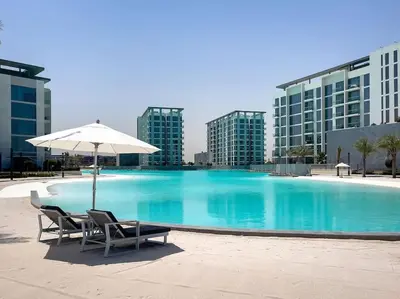 a swimming pool with two chairs and an umbrella at Aesthetic 1Br Chrystal Lagoon in Dubai