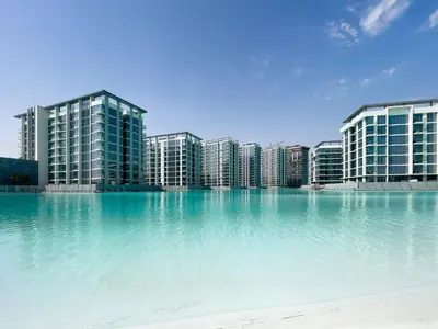 a large body of water in front of tall buildings at Aesthetic 1Br Chrystal Lagoon in Dubai