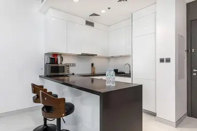 a kitchen with a counter and two chairs in it at Aesthetic 1Br Chrystal Lagoon in Dubai