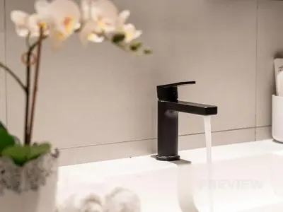 a bathroom sink with a black faucet and flowers at Magnificent Studio, Burj Khalifa view, Marquise Sq in Dubai