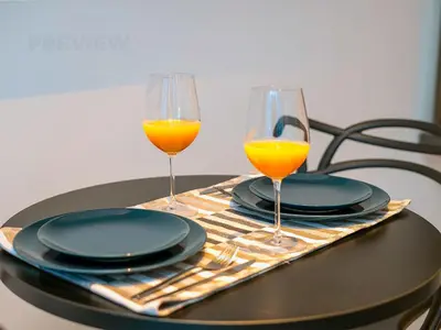 two glasses of orange juice and plates on a table at Magnificent Studio, Burj Khalifa view, Marquise Sq in Dubai