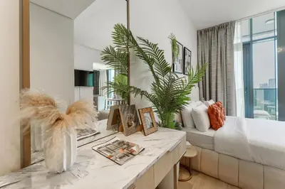 a living room with a bed and a large window at Stylish Studio with Gym & Pool Access in Dubai