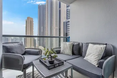 a couch on a balcony with a view of a city at Sky-High 1BR with Breathtaking Burj Khalifa View in Dubai