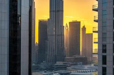 a view of a city skyline at sunset at Sky-High 1BR with Breathtaking Burj Khalifa View in Dubai