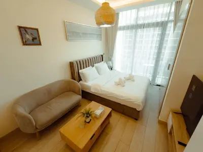 a small bedroom with a bed and a couch and a table at Chic Studio with Balcony, Netflix and Chill Pet-free in Dubai