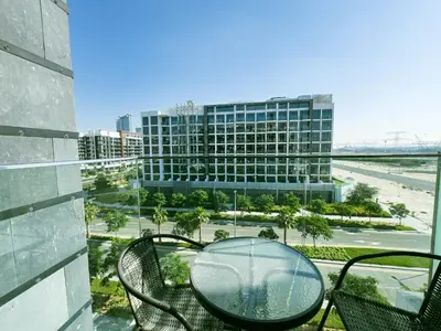 a glass table and chairs on a balcony with a building at Chic Studio with Balcony, Netflix and Chill Pet-free in Dubai
