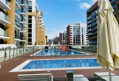 a swimming pool with an umbrella and some buildings at Chic Studio with Balcony, Netflix and Chill Pet-free in Dubai