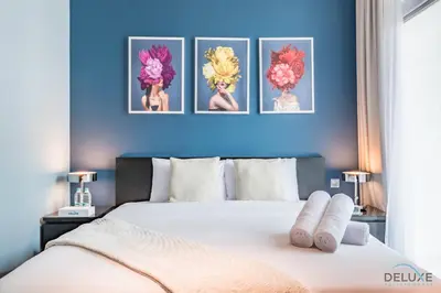 a bedroom with a bed with four pictures on the wall at Charming 3BR Townhouse with Study Room in Damac Hills 2 Centaury, Dubailand By Deluxe Holiday Homes in Dubai