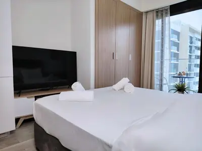 a bedroom with a large white bed and a flat screen tv at Netflix and Wi-Fi Studio Pool, Gym & City Views in Dubai