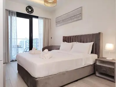 a bedroom with a large white bed with a large window at Netflix and Wi-Fi Studio Pool, Gym & City Views in Dubai