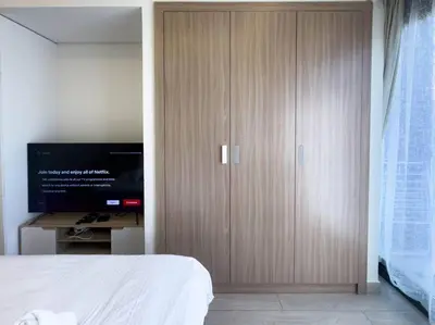 a bedroom with a large wooden cabinet with a flat screen tv at Netflix and Wi-Fi Studio Pool, Gym & City Views in Dubai