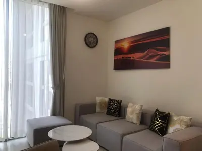 a living room with a couch and a clock on the wall at Fast Wi-fi Netflix Cozy 1BR Flat Near Downtown Dubai in Dubai