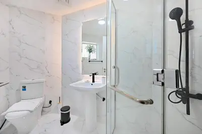 a white bathroom with a sink and a shower at Stunning 2 Bed Great Metro access in Dubai
