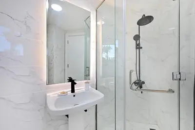 a white bathroom with a sink and a shower at Stunning 2 Bed Great Metro access in Dubai