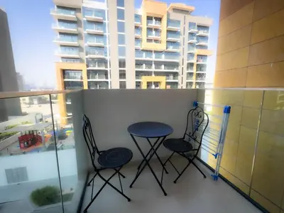 two chairs and a table on a balcony with a building at Lavish Studio Pool Gym, Balcony, Netflix Fast Wi-Fi in Dubai