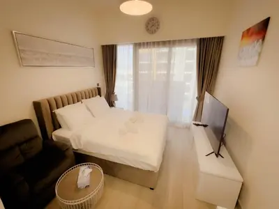 a bedroom with a bed and a couch and a television at Lavish Studio Pool Gym, Balcony, Netflix Fast Wi-Fi in Dubai
