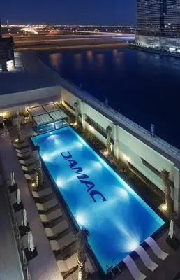 a large swimming pool on top of a building at night at In Vogue Live On the Canal in Business Bay in Dubai