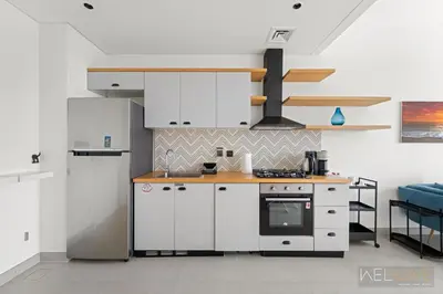 a kitchen with white cabinets and a stove at WelHome - Beautiful 1BR Apt in Dubai Hills with City View in Dubai