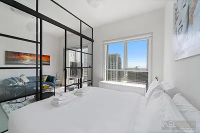 a white bedroom with a large bed and large windows at WelHome - Beautiful 1BR Apt in Dubai Hills with City View in Dubai