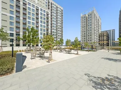a courtyard with tables and chairs and buildings at WelHome - Beautiful 1BR Apt in Dubai Hills with City View in Dubai