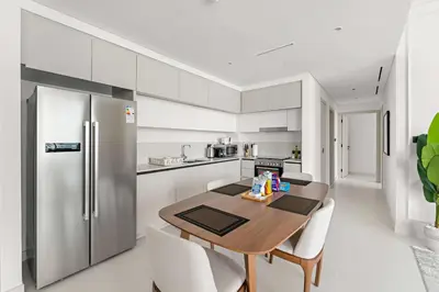 a kitchen with a wooden table and a stainless steel refrigerator at Silkhaus Family Ideal & High Floor 2BDR in Dubai