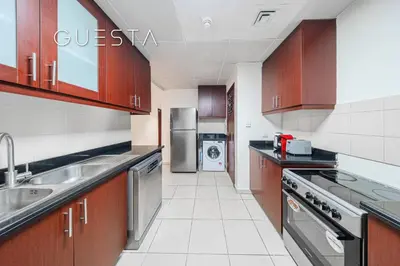 a kitchen with stainless steel appliances and wooden cabinets at Jumeirah Beach Residence - Bahar 1, Dubai Marina in Dubai