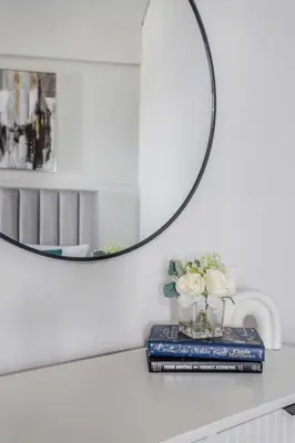 a table with a mirror and a book and flowers at Frank Porter - Aykon City Tower in Dubai
