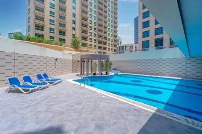 a swimming pool with two blue chairs next to a building at Full Sea View in Dubai Marina - Balcony & Pool in Dubai