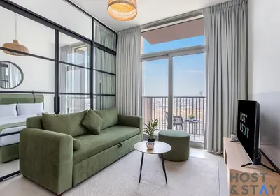 a living room with a couch and a bed and a television at Elegant 2-BR Retreat In Dubai Hills in Dubai