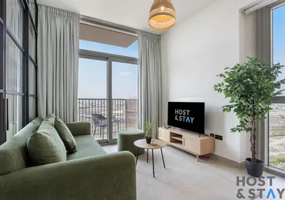 a living room with a green couch and a tv at Elegant 2-BR Retreat In Dubai Hills in Dubai