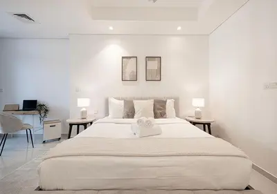 a white bedroom with a large bed with two tables at Bright High Floor Apartment in a 5 Star Hotel Resident Tower w Burj View and access to 64th Infinity Pool, Gym, Sauna, Spa, Restaurants, Bars and more in Dubai