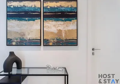 three paintings hanging on a wall with a bench at Chic Urban 2BR at Collective 2 in Dubai